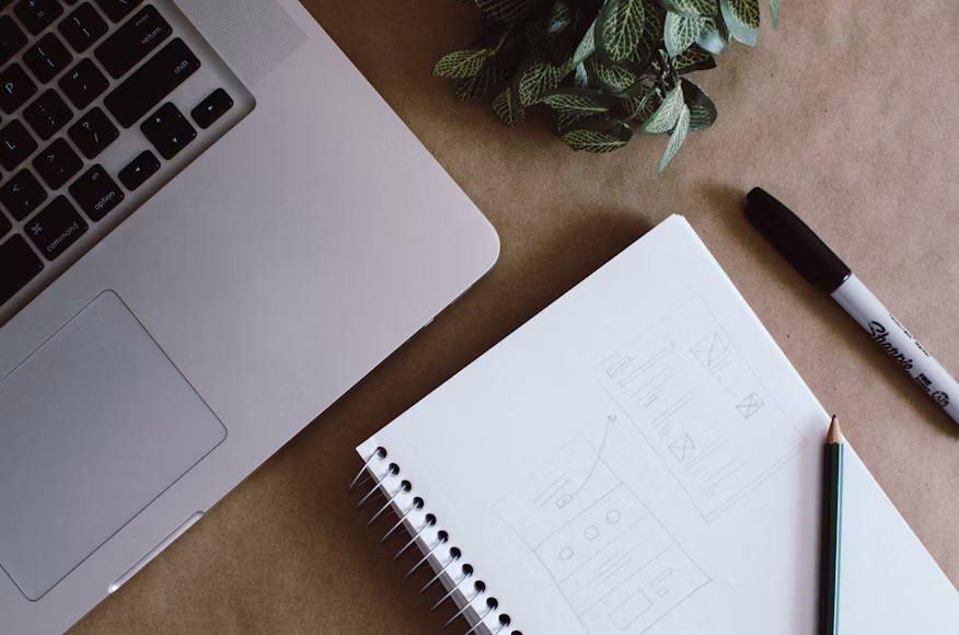 Espacio de trabajo con laptop, cuaderno de bocetos y marcador